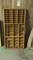 Front view of vintage wooden printers press tray with multiple small compartments of varying sizes