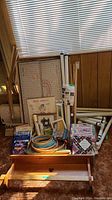 Wide shot of the quilting supplies collection including frame parts, books, hoops, thread, and the wall shelf.