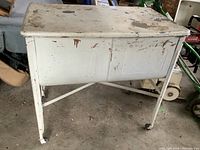 Front view of the antique metal double sink showing overall structural form and peeling paint.