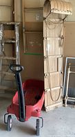 Wooden toboggan and Radio Flyer plastic wagon side by side in garage space with the wagon handle visible