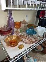 Overview photo showing the assortment of vintage glass bowls, candy dishes, bottle, and milk glass jug arranged on a shelf.