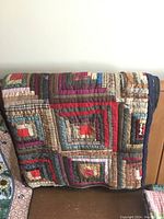 The quilt folded over a couch, showing the square patchwork design with various colors and fabrics.