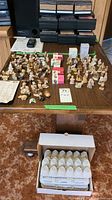 Large collection of Wade porcelain figurines on display table with some original boxes and egg carton packing visible underneath.