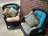 Front and side view of a large brown wicker chair with blue and patterned cushions.