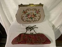 Front view of larger beige purse and smaller red purse on white fabric background