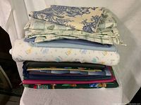 Stack of various folded fabric pieces on a white backdrop showing different patterns and colors.