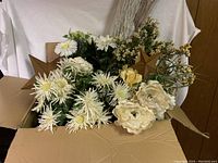 Box filled with assorted artificial flowers and wooden star decorations from a front angle