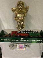 Full view of gold angel tree topper above boxed Christmas express train set with power cord