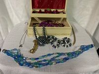 Jewelry box with assorted necklaces, bracelets, and rings arranged around and inside the box