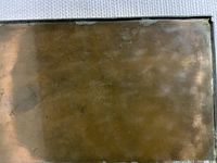 Photo of the bottom of the metal box showing the stamped marking in the center.