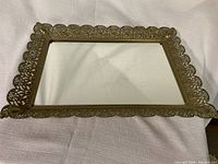 Rectangular mirror dresser tray with ornate gold metal scalloped border and clear mirror surface.