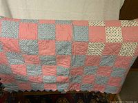Front side of quilt showing checkered patchwork pattern with pink, floral, and geometric fabric squares.