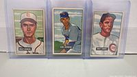 Three 1951 Bowman baseball cards featuring Billy DeMars, Earl Johnson, and Walt Dubiel in protective sleeves.