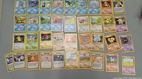Photo showing a large selection of 34 Pokemon cards laid out flat including various Water, Psychic, and other types and Trainer cards.