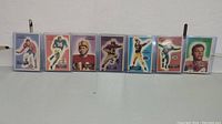 Full set of seven 1955 Bowman football cards, showing a variety of players and team colors.