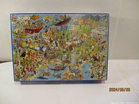Full front view of the puzzle box showing colorful cartoon artwork of a bustling scene with boats, castle, and many characters, indicating the puzzle piece count (5000 pieces) and brand Jumbo.