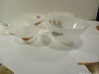 Five Arcopal bowls with floral decals arranged on a white surface, showing size variation and design.
