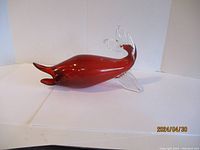 Side view of the art glass fish showing elongated body and clear fin details, placed on white background.