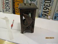 Front view of cast iron candle holder showing fish design and size reference.