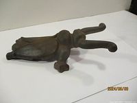 Metal boot jack shown from side angle revealing its beetle-like insect design and curved legs.