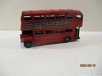 Side angle of red metal London double-decker bus model showing destination names and windows.