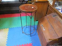 Full view of metal frame plant stand showing four legs and curved supports.