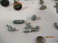 Close-up showing detailed metal Monopoly tokens including a rocket ship, dog, thimble, and a boot.
