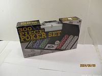 Front and side view of sealed 300 piece poker set box in aluminum case showing chips and playing cards image