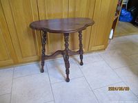 Side view of the wooden table showing carved edges and turned legs.