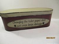 Front view of the rectangular metal container showing the humorous text 'Changing the toilet paper does not cause brain damage'