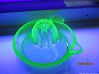 Top view of uranium glass citrus reamer showing juicing cone and reservoir bowl under black light.