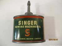 Close-up photo of the vintage Singer sewing machine oil can with green and red color scheme and company logo.