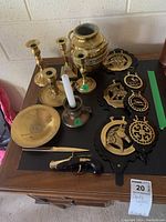 Top view of lot showing candlesticks, brass vase, ashtray, letter opener, and brass leather wall hangings with horse and ship motifs