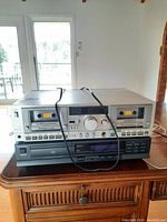 Front view showing stacked Technics M202 RS-M202 dual cassette deck on top of Panasonic SL-PS352 CD player on wooden surface.