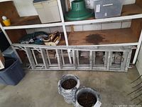 Side view showing the full length of the aluminum folding ladder with 6 steps resting on the floor against shelving.