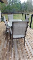 Overhead view of the outdoor dining table with four chairs arranged around it on a wooden deck, showing the table's plastic top and chair design.