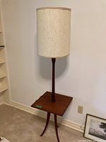 Front view of solid teak lamp with integrated square side table on tripod legs