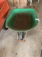 Front-top view of green metal tray of the wheelbarrow showing wear and surface rust inside the tray.