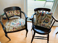 Pair of vintage oak armchairs side by side, one upholstered with floral and bird patterned fabric, one solid oak spindle back chair, showing wear and tear.