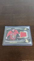 Front of David Rundblad jersey card showing photo of player and embedded red fabric swatch with numbering 220/799.