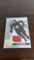 Front of Natalie Spooner hockey jersey card showing player image and embedded red jersey swatch