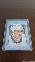 Front view of the William Nylander rookie hockey card in a clear protective plastic case. Card shows Nylander's portrait, the P-57 Rookie Portraits design, and his name.