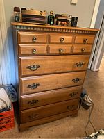 Front view of the wooden dresser with decorative metal handles and three small top drawers.