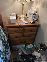 Front and top view of wooden 2-drawer nightstand with items on top and visible scratches and scuffs on the surface.