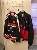 Two NASCAR racing jackets with visible sponsor logos Goodwrench, GM, and large numbers 3 and 8 on front, hanging on hooks.