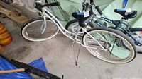 Side view of white Schwinn Cruiser SS bike with blue trim parked on concrete floor, showing frame, wheels, and handlebars.