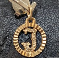 Front close-up showing texture and design of the letter 'J' inside the oval frame on the pendant.