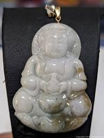 Front view of hand-carved jadeite Buddha pendant with 14K gold bail on black background.