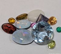 Photo showing a group of 12 loose mixed colorful genuine gemstones in various cuts and shapes.