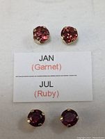 Front view of garnet and ruby earrings with a card indicating month stones January (Garnet) and July (Ruby)